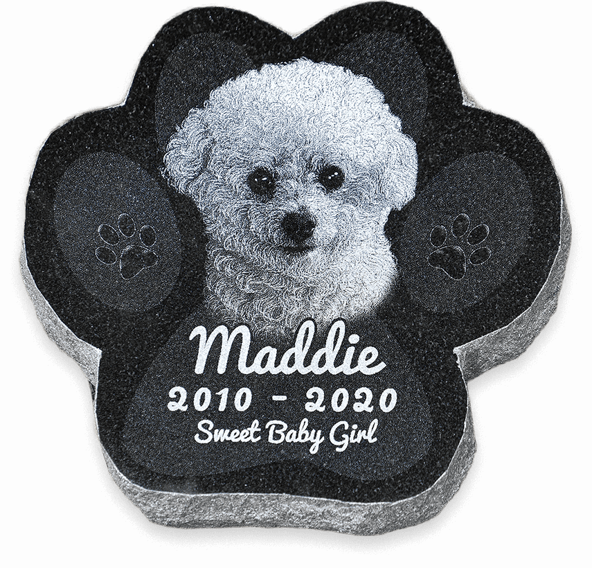 Flat paw-shaped granite grave marker for a garden burial, engraved with a dog's photo and name.