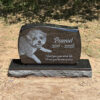 Custom granite dog memorial stone for Peanut displayed in a backyard garden.