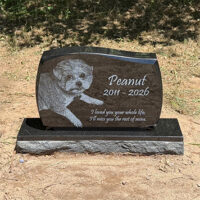 Custom granite dog memorial stone for Peanut displayed in a backyard garden.
