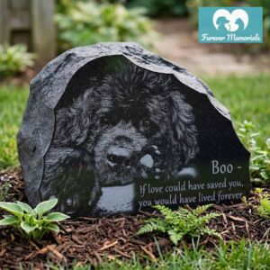 Rustic black granite pet memorial engraved with a detailed portrait of Boo the dog, featuring the inscription “If love could have saved you, you would have lived forever,” placed in a garden setting.