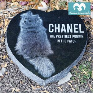 Custom engraved black granite heart-shaped pet memorial for dog Chanel featuring full-body portrait engraving and inscription “The Prettiest Punkin in the Patch,” displayed in a garden setting