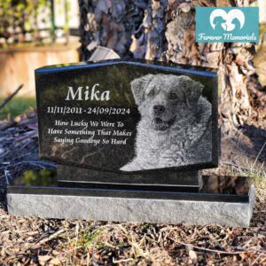 Custom engraved black granite upright pet memorial for dog Mika with detailed portrait engraving and inscription, displayed in an outdoor garden setting