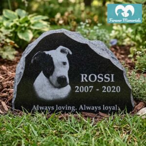 Rustic black granite pet memorial engraved with a portrait of Rossi the dog, including the inscription “Always loving. Always loyal.” and the dates 2007–2020, displayed in a garden setting.