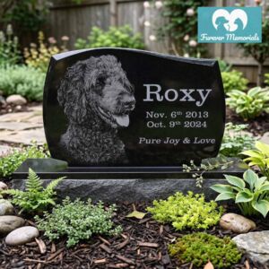 Black granite upright pet memorial stone engraved with a portrait of a poodle named Roxy with the dates November 6, 2013 – October 9, 2024, placed in a landscaped garden setting.