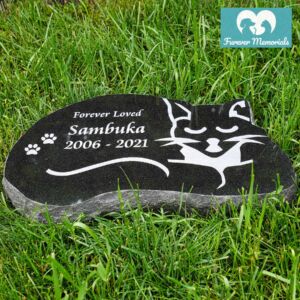 Black granite cat-shaped pet memorial stone engraved with a sleeping cat silhouette for Sambuka, featuring the inscription “Forever Loved,” the dates 2006–2021, and paw prints, placed in green grass.